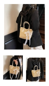 Close-up of woven straw bucket bag featuring white lace bow and pearl charm accents