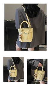 Close-up of litchi grain texture on yellow bucket bag with cute cartoon pendant