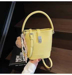 Detail of yellow lychee leather bucket bag with cute bear charm and adjustable strap
