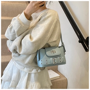 Détail du sac à bandoulière en similicuir bleu clair avec œillets et boucle en métal