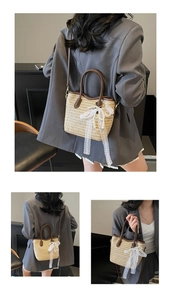 Detail of contrast straw bucket bag with white lace bow and brown leather handles