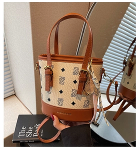 Close-up of leather bucket bag with bear print, tennis racket charm, and mirror reflection