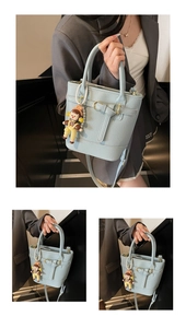 Detail of light blue lychee texture bucket bag with cartoon doll and shoulder strap