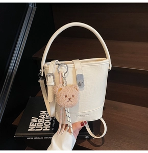 White litchi leather bucket bag detail with metal lock and cute plush bear charm