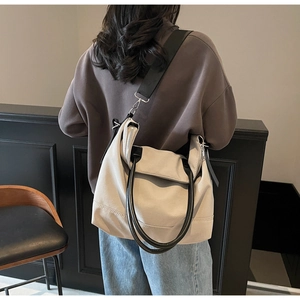 Détails arrière d'un grand sac cabas beige doté d'une bandoulière noire réglable et large