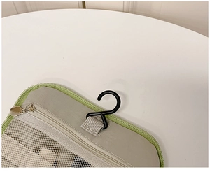 Detail view of grey fabric hanging toiletry bag with mesh pockets and S-shaped hook
