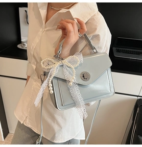 Détail du sac en cuir bleu clair ciré avec nœud en dentelle de perles et fermoir rotatif