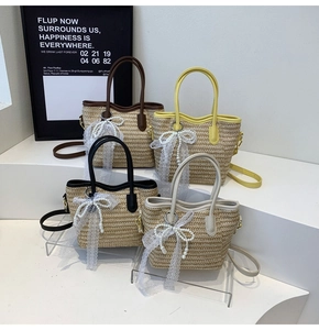 Detail of hand-woven straw bucket bag with lace bow pearl charm on minimalist white steps