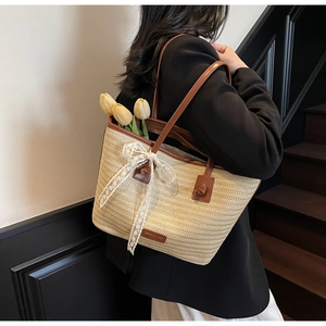 Détail d'un grand sac cabas en paille avec lanières en cuir et nœud en dentelle blanche