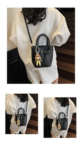 Detail of black lychee texture bucket bag with doll charm and pearl chain accent