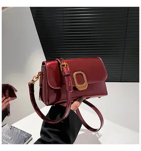 Gros plan d'un sac bandoulière vintage en cuir verni bordeaux avec boucle dorée chic