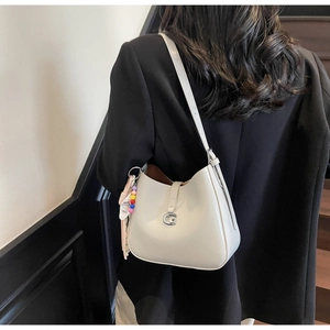 Detail view of grey semi-circle hobo bag featuring silver G buckle and tassel charm