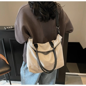 Vue de dos d'un mannequin portant un grand sac cabas en toile crème et anses en cuir