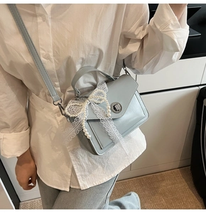 Sac carré en similicuir bleu clair avec nœud en dentelle et perle porté par mannequin