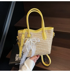 Detail of hand-held straw bucket bag with yellow leather trim and lace bow decoration