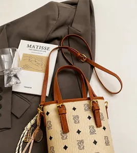 Detail shot of cream bucket bag with bear print and tennis racket tassel charm