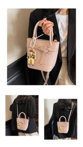 Detail view of pink lychee leather bucket bag with cute charm and adjustable strap