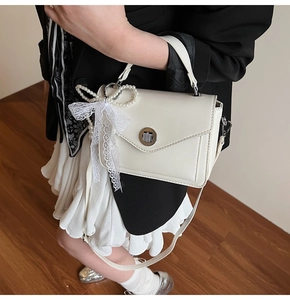 Détail du sac en cuir huilé blanc avec nœud de perles et ruban en dentelle élégant