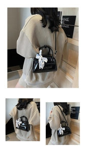 Detail of black patent leather Boston bag with blue checkered silk scarf and bow