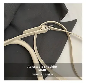 Close-up of beige adjustable faux leather shoulder strap with silver buckle detail