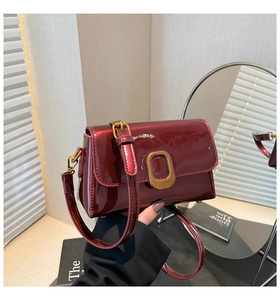 Détail d'un sac en cuir verni bordeaux avec finition brillante et boucle dorée