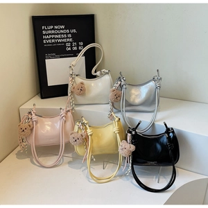 Detail view of colorful glossy patent leather underarm bags with cute plush bear charms