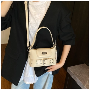 Vue détaillée du sac seau crème avec ceinture à rivets et fermeture à verrou rotatif