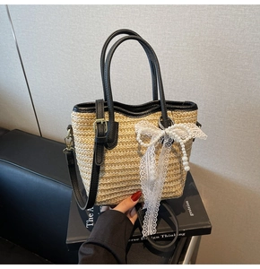 Detail of woven straw bucket bag featuring lace bow and pearl charms on book
