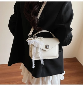 Détail du sac bandoulière blanc crème avec nœud en dentelle et chaîne de perles