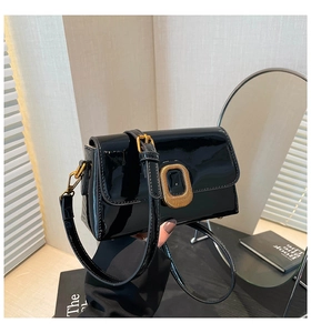 Détail d'un sac en cuir verni noir avec boucle ovale dorée au style rétro chic