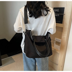Détail d'un grand sac fourre-tout noir en nylon porté par un mannequin pour l'échelle