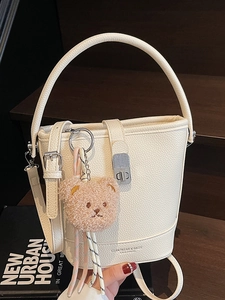Minimalist beige bucket bag in lychee pattern leather with a cute plush bear charm