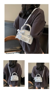 Detail of light blue Boston bag with ribbon handle and bow, shown on fashion model
