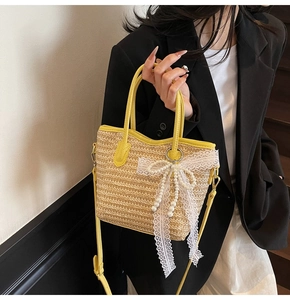 Detail of hand-woven straw bucket bag with yellow leather trim and lace bow decoration