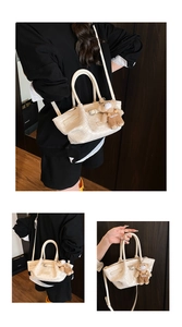Close-up of white woven bucket bag with teddy bear pendant and adjustable strap