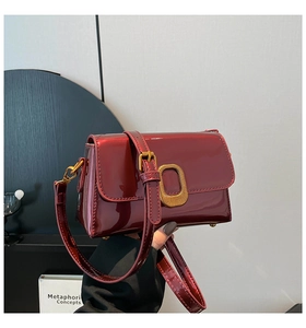 Détail d'un sac bandoulière en cuir verni rouge foncé avec boucle dorée vintage