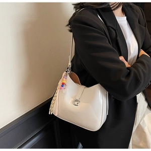 Close-up of white glossy patent leather hobo bag with silver buckle and bead charm