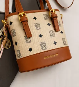 Detail of white bucket bag featuring bear patterns and brown leather strap with metal buckle