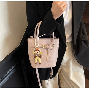 Detail of pink lychee pattern bucket bag with cute doll charm and leather strap