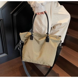 Détail d'un grand sac fourre-tout en toile olive avec anses noires et fermeture éclair