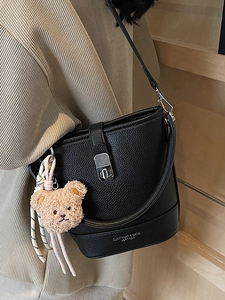 Minimalist black lychee leather bucket bag with silver lock and plush toy pendant