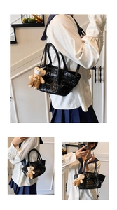 Detail view of black woven tote bag with a plush bear charm and silver buckle strap