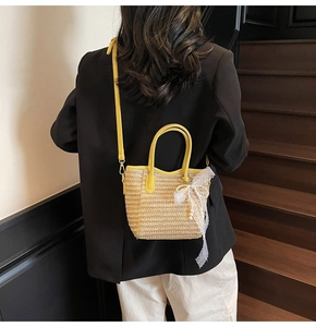 Detail of straw bucket bag with yellow leather strap and white lace pearl bow decoration