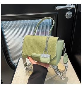 Detail of light green crossbody bag with woven texture and ethnic print wide strap