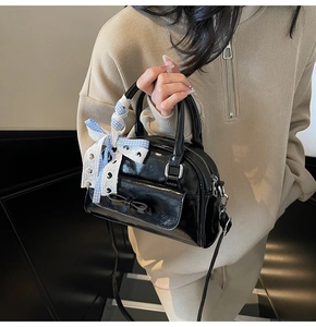 Detail of black patent leather Boston bag with decorative bows and lace ribbon trim