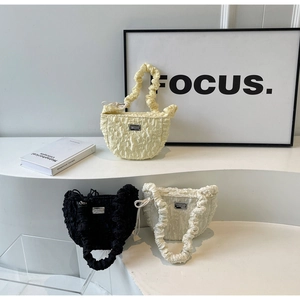 Detailed texture of ruffled cloud handbags in yellow, black, and off-white with metal plates