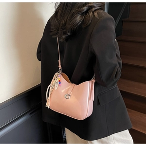 Pink glossy patent leather underarm bag with silver G-buckle worn by a model