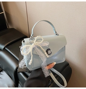 Détail du sac à main bleu clair en similicuir avec nœud en dentelle perlée et boucle