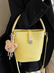 Yellow leather bucket bag with top handle, silver twist lock and plush bear charm