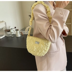 Detail of light yellow ruched cloud bag with textured pleats and metal brand plaque